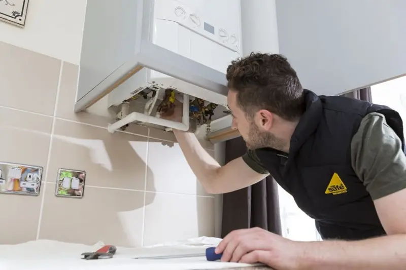 Gas Safe engineer servicing a wall-mounted boiler